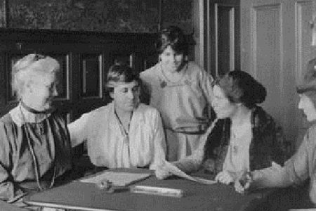 an image of a group of women in fancy clothing standing around a table