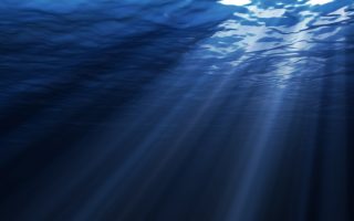 an image of a deep blue ocean with sunbeams shining through the water