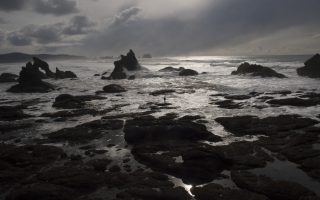 an image of a person standing on a rock in the ocean
