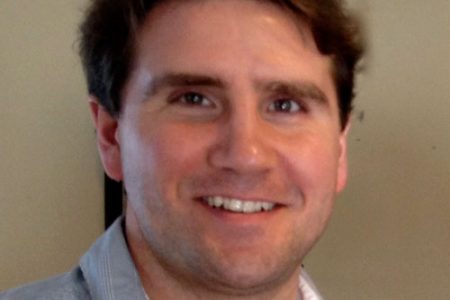 an image of a man smiling while holding a wine glass